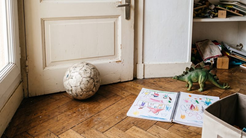 Ballon de football contre une porte, carnet de croquis ouvert et figurine de dinosaure sur un parquet